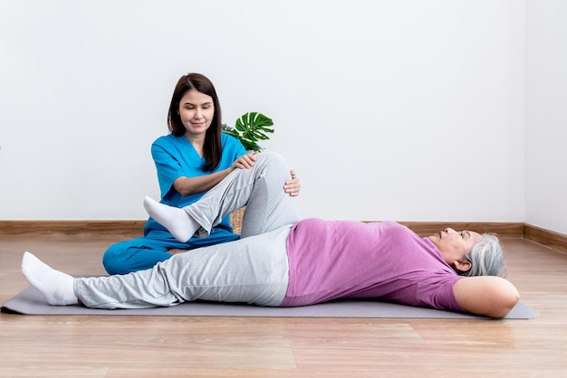 Physical therapist Asian woman doing leg physiotherapy for elderly woman to treat osteoarthritis