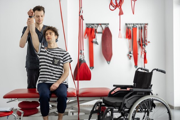 Physical therapist examines young male patient at clinic