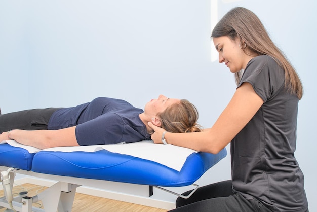 A physical therapist treats a patient's neck and cervical