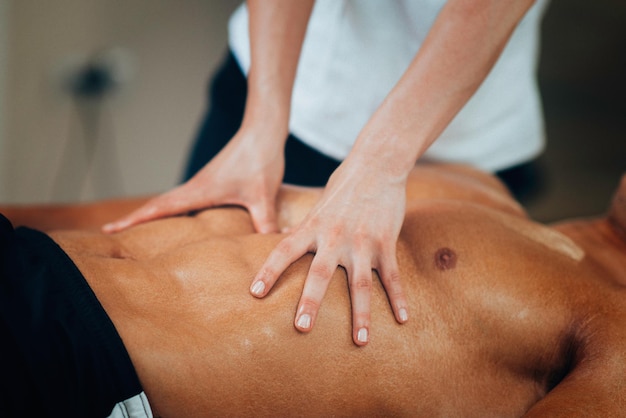 Physical therapyst massaging sportsman's stomach