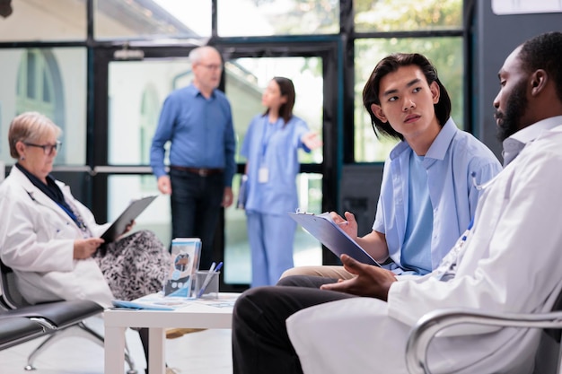 Physician medic explaining health care treatment to asian patient during checkup visit consultation in hospital office. Young man signing medical papers before start examination. Medicine service