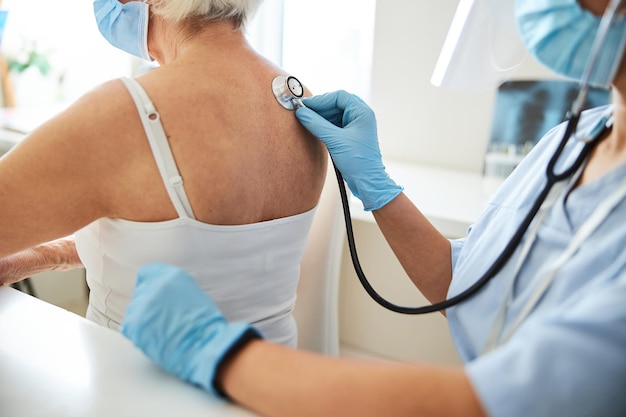 Photo physician putting a stethoscope resonator to a person shoulder blade