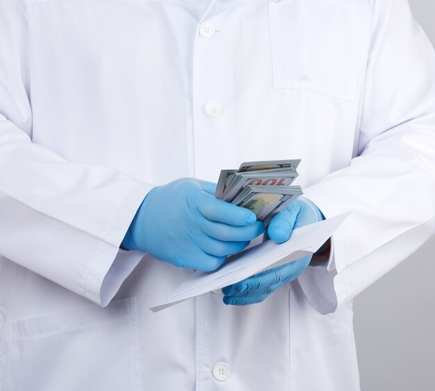 physician in a white coat, wearing blue sterile gloves, doctor holds a pack of paper money, anti-corruption concept