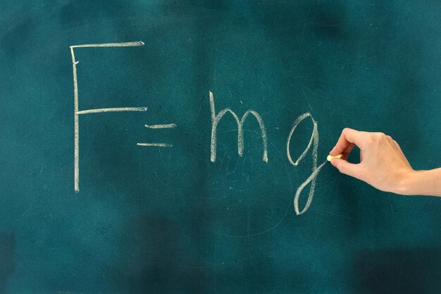 Physics formula written on blackboard with chalk