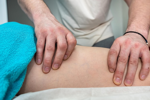 Physio therapist doing healing massage on female leg