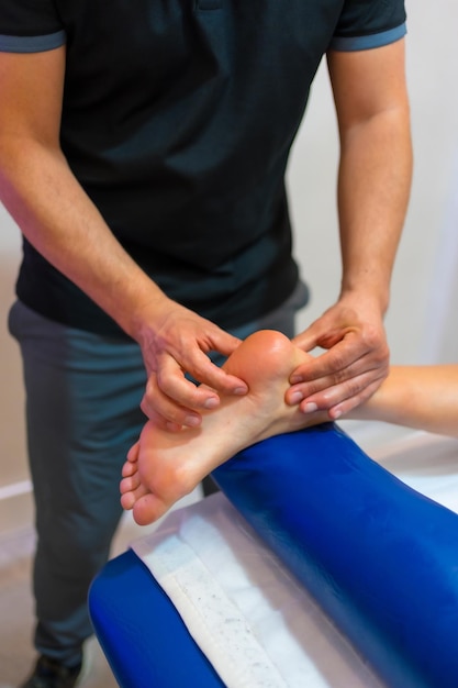 Photo physiotherapeutic massage to an unrecognizable woman lying on a stretcher on the foot