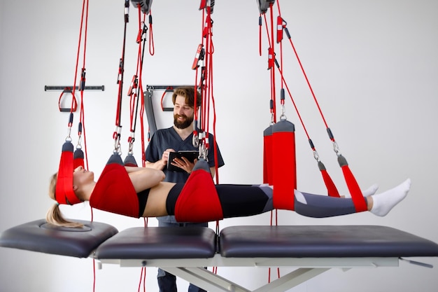 Physiotherapist doctor with clipboard watching female patient hanging