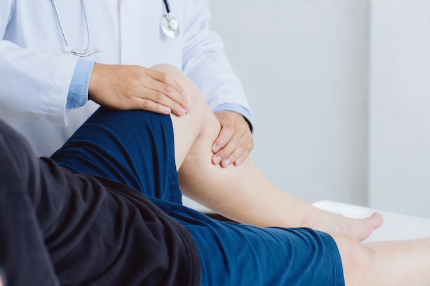 Physiotherapist doctor working examining treating injured leg of male patient and giving exercising leg treatment male patient in physio clinic .