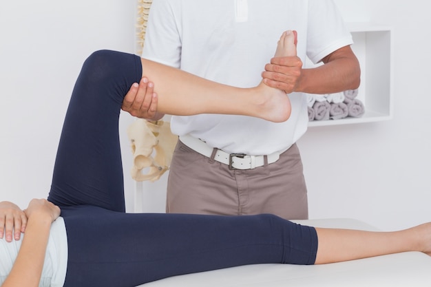 Physiotherapist doing leg massage to his patient