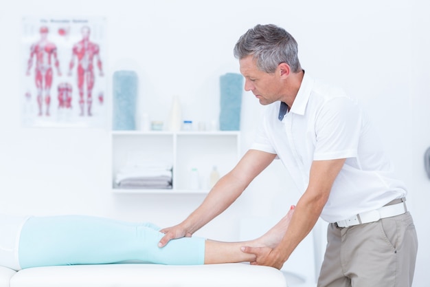 Physiotherapist doing leg massage to his patient