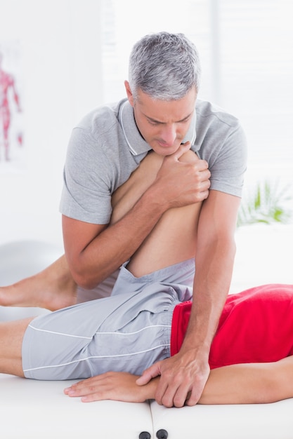 Physiotherapist doing leg stretching to his patient in medical office