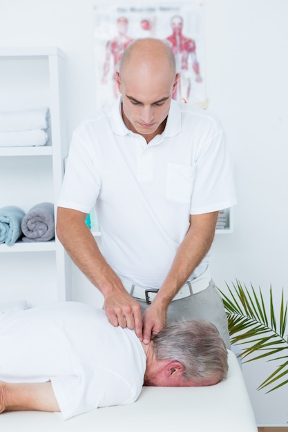 Физиотерапевт делает массаж шеи пациенту