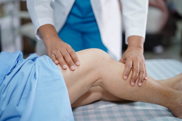 Physiotherapist doing physical therapy in rehab with patient in hospital.