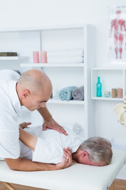 Physiotherapist doing shoulder massage to his patient