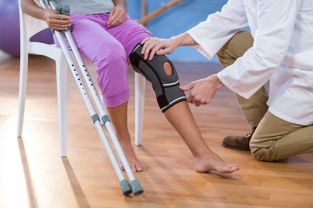 Photo physiotherapist examining female patients knee