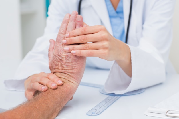 Physiotherapist examining male patients wrist