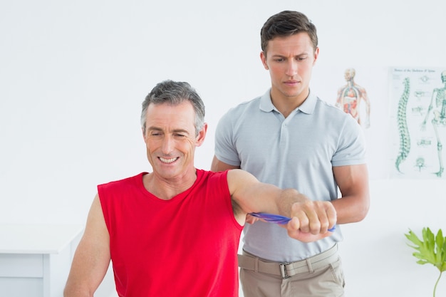 Physiotherapist examining a smiling mature mans arm