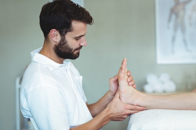 Physiotherapist giving foot massage to a woman