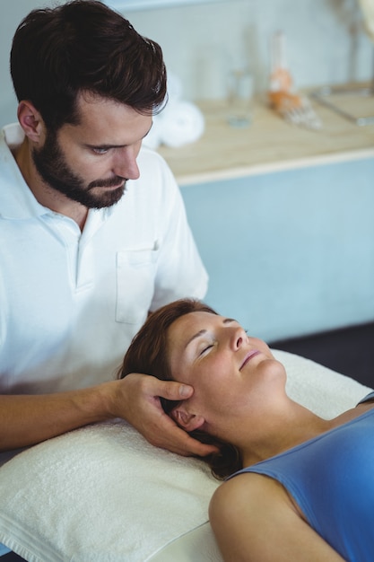 Физиотерапевт делает массаж головы женщине