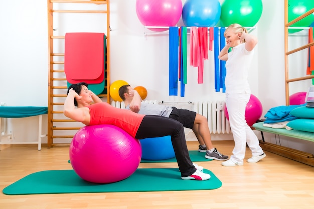 Physiotherapist giving patients gymnastic exercise