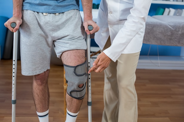 Physiotherapist helping patient to walk with crutches