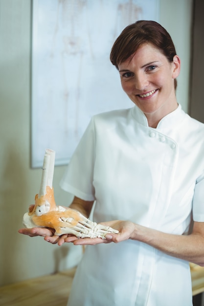 Physiotherapist holding a skeleton feet model