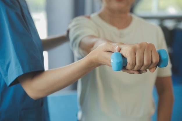 Physiotherapist man giving exercise with dumbbell treatment About Arm and Shoulder of athlete male patient Physical therapy concept