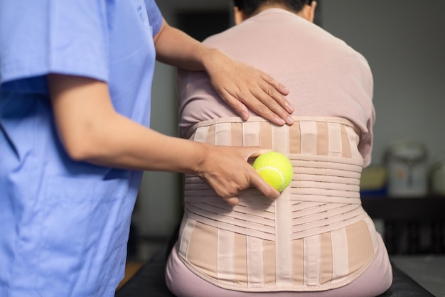 Физиотерапевт массирует спину пациента мячом в больнице Концепция физиотерапии