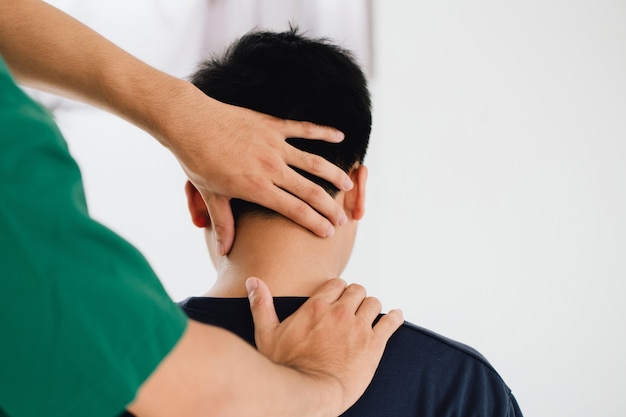 physiotherapist massage therapist holding male clients head and massaging tight neck muscles