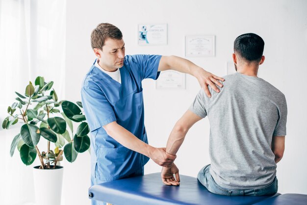 Fisioterapista che massaggia il braccio del paziente sul lettino da massaggio in ospedale