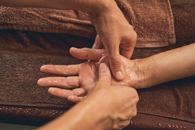 physiotherapist massaging palm of a man in the spa luxury resort