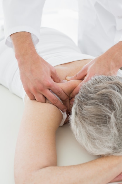 Foto fisioterapista che massaggia indietro un womans anziano