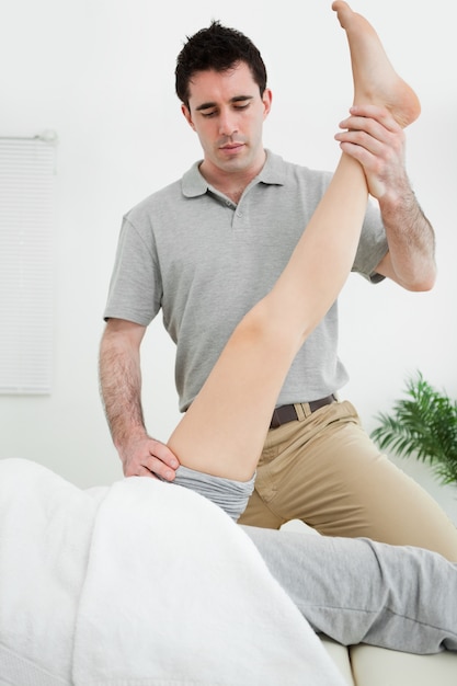 Physiotherapist raising the leg of a patient