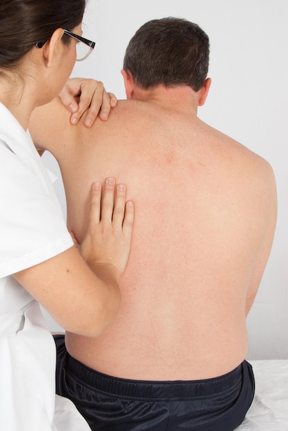 Physiotherapist stretching a man back in medical office