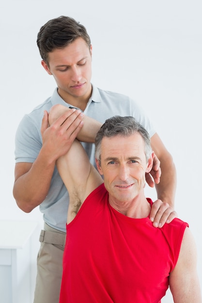 Physiotherapist stretching a smiling mature mans arm