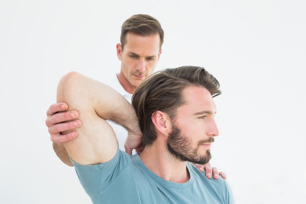 Physiotherapist stretching a young mans arm