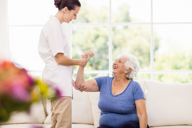 Physiotherapist taking care of sick elderly patient at home