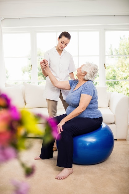 Physiotherapist taking care of sick elderly patient at home