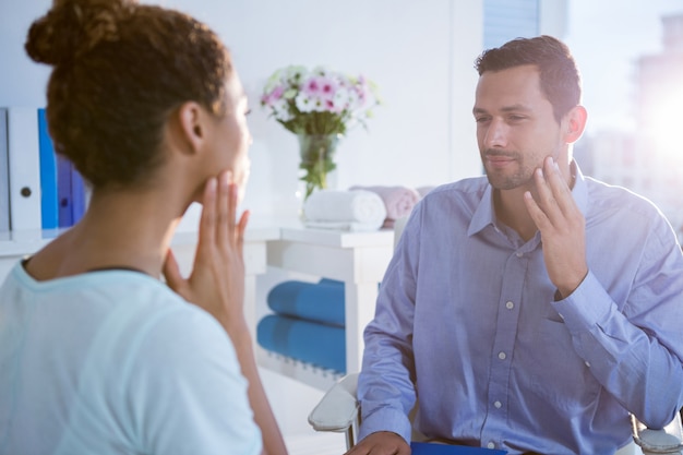 Photo physiotherapist talking with patient with neck pain