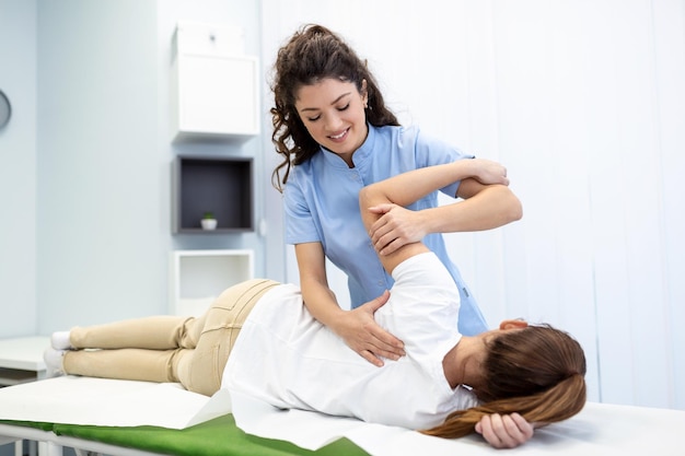 물리 치료사 치료 환자 손을 잡고 어깨 관절 치료 환자와 상담하는 물리 치료사 어깨 근육 통증 문제 물리 치료 진단 개념