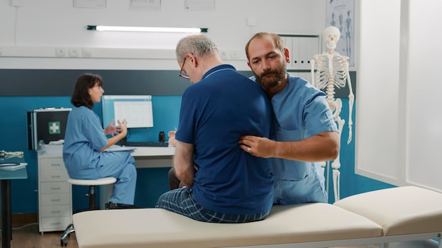 Physiotherapist using bones cracking procedure on elder patient to treat mechanical disorders at recovery appointment. Osteopath helping old man with physical injury, doing alternative medicine.