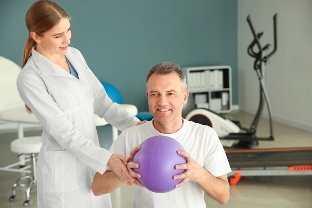 Physiotherapist working with mature patient in rehabilitation center