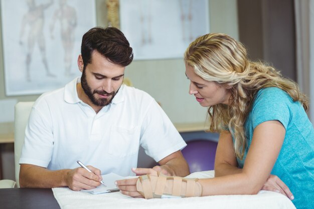 Physiotherapist writing report next to the patient