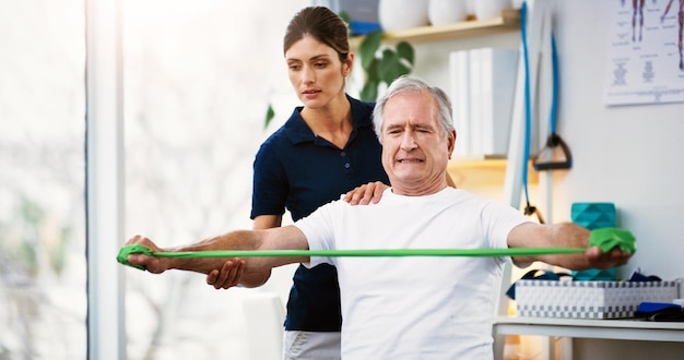 Physiotherapy senior man and doctor exercise resistance band and workout for muscle rehabilitation in a clinic Physiotherapist elderly patient and training stretching muscles and body fitness