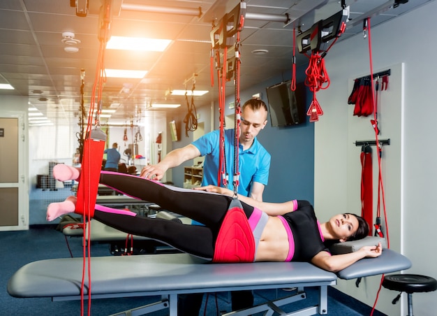 Physiotherapy. Suspension training therapy. Young woman doing fitness traction