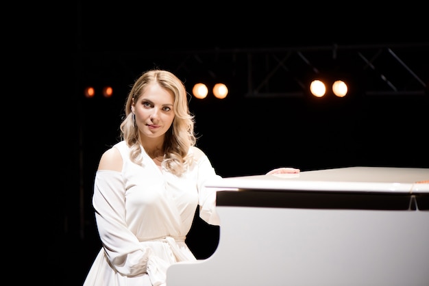 Pianist poseren in de buurt van witte piano op het podium