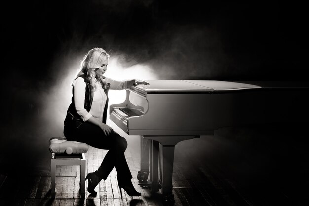 Photo pianist posing near white piano on the stage