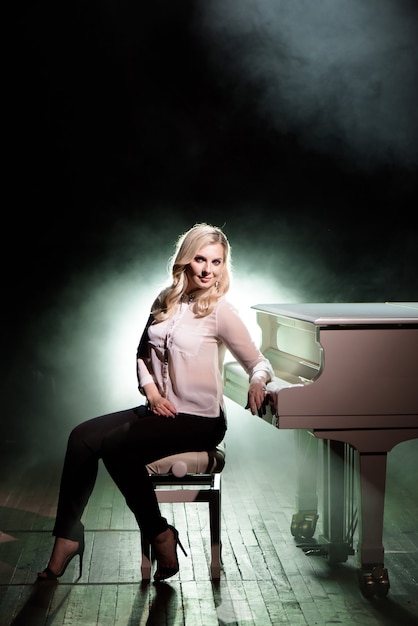 Pianist posing near white piano on the stage.