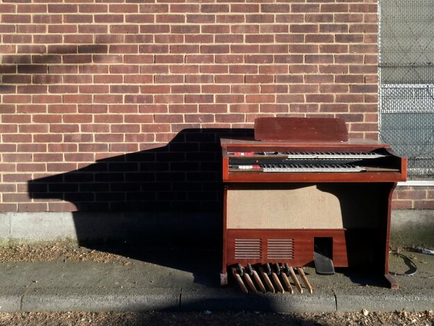 Foto pianoforte contro un muro di mattoni durante una giornata di sole