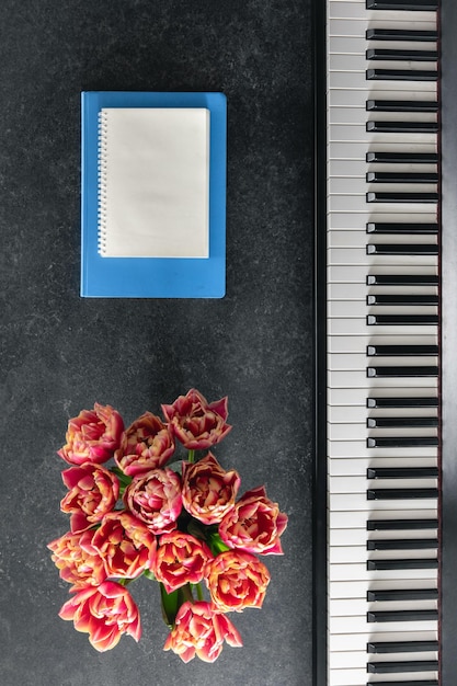 Piano boeket van bloemen en notitieblokken op een donkere achtergrond top view